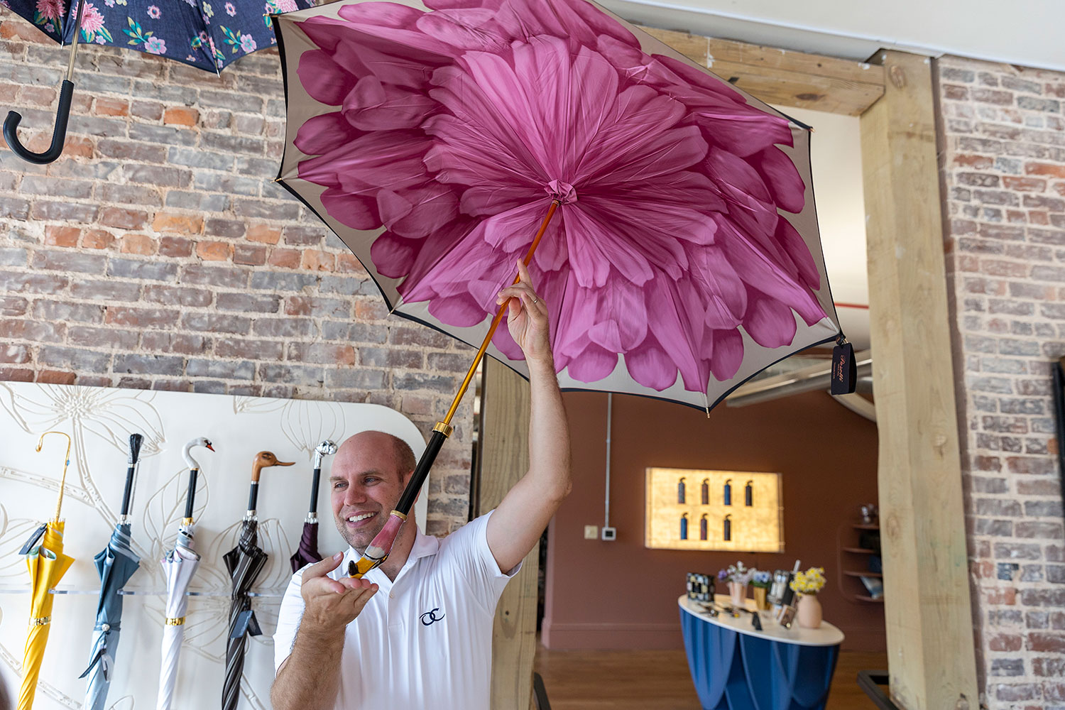Co-owner Robert Buhler shows off a collection of handcrafted designer umbrellas in the gift shop.