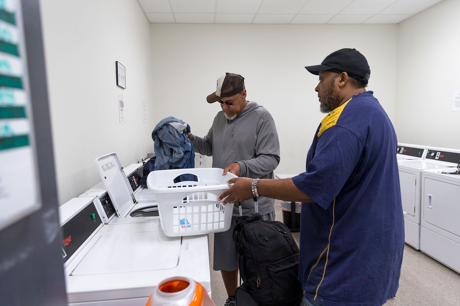 Basic Needs Coordinator Otis Whitaker, right, helps a guest in the laundry facility.